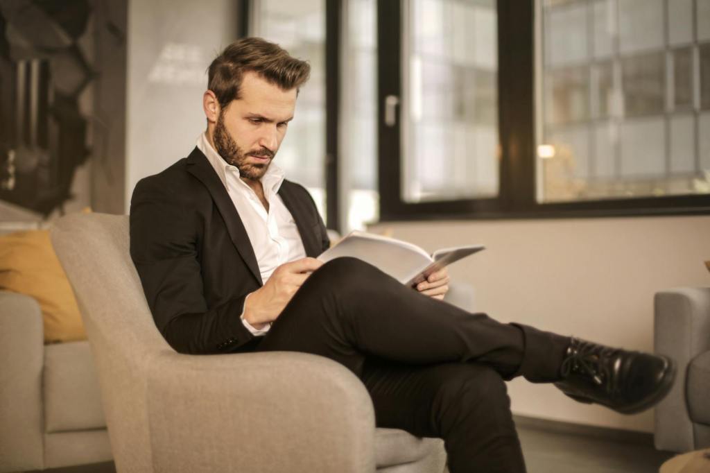 man in black suit sitting on brown couch