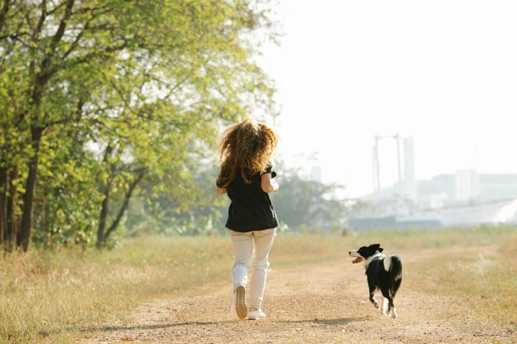faceless woman and collie dog running together in nature